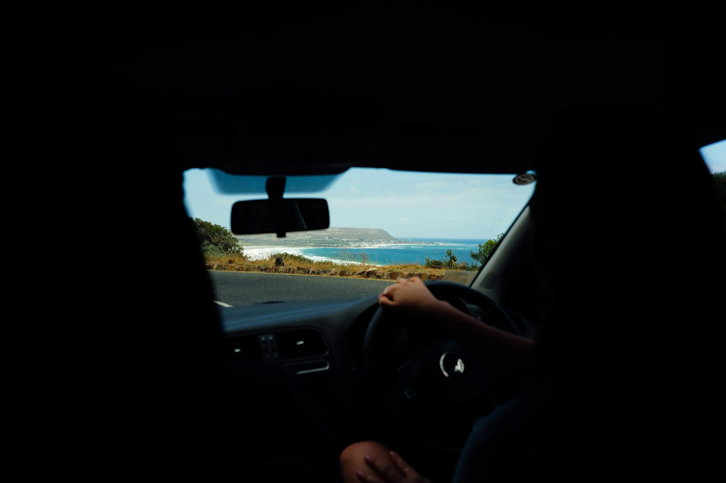 A coastal road seen through a car windshield